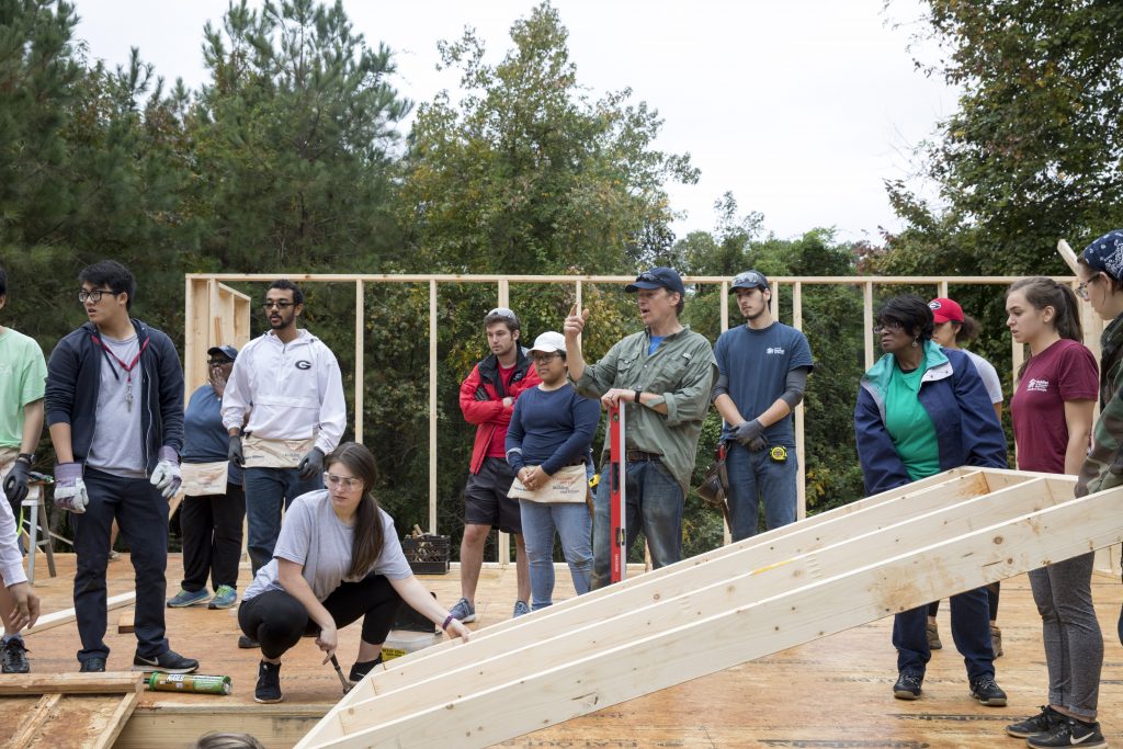 students pushing a wooden structure up in Habitat for Humanity event