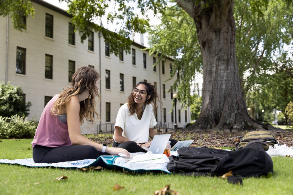 two students are talking on the lawn